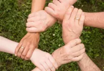 Hände halten sich gegenseitig fest und helfen so einander gegenseitig stärker zu sein.