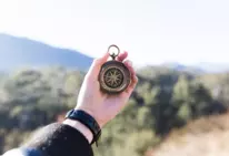 Ein Mensch hält einen Kompass in der Hand und überlegt sich, wo es hingehen soll.