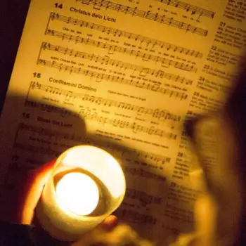 Eine Kerze wird vor ein Liedblatt gehalten.